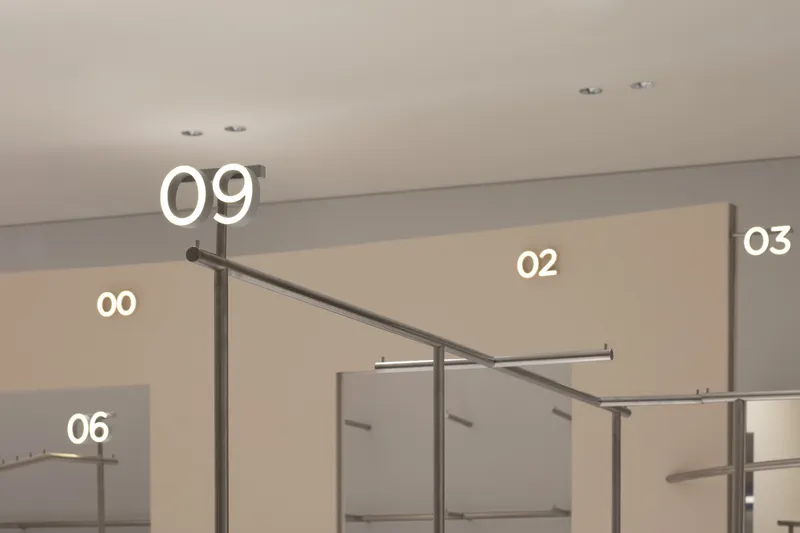 Interior view of slender metal clothing racks with diagonal bracing beneath a beige ceiling