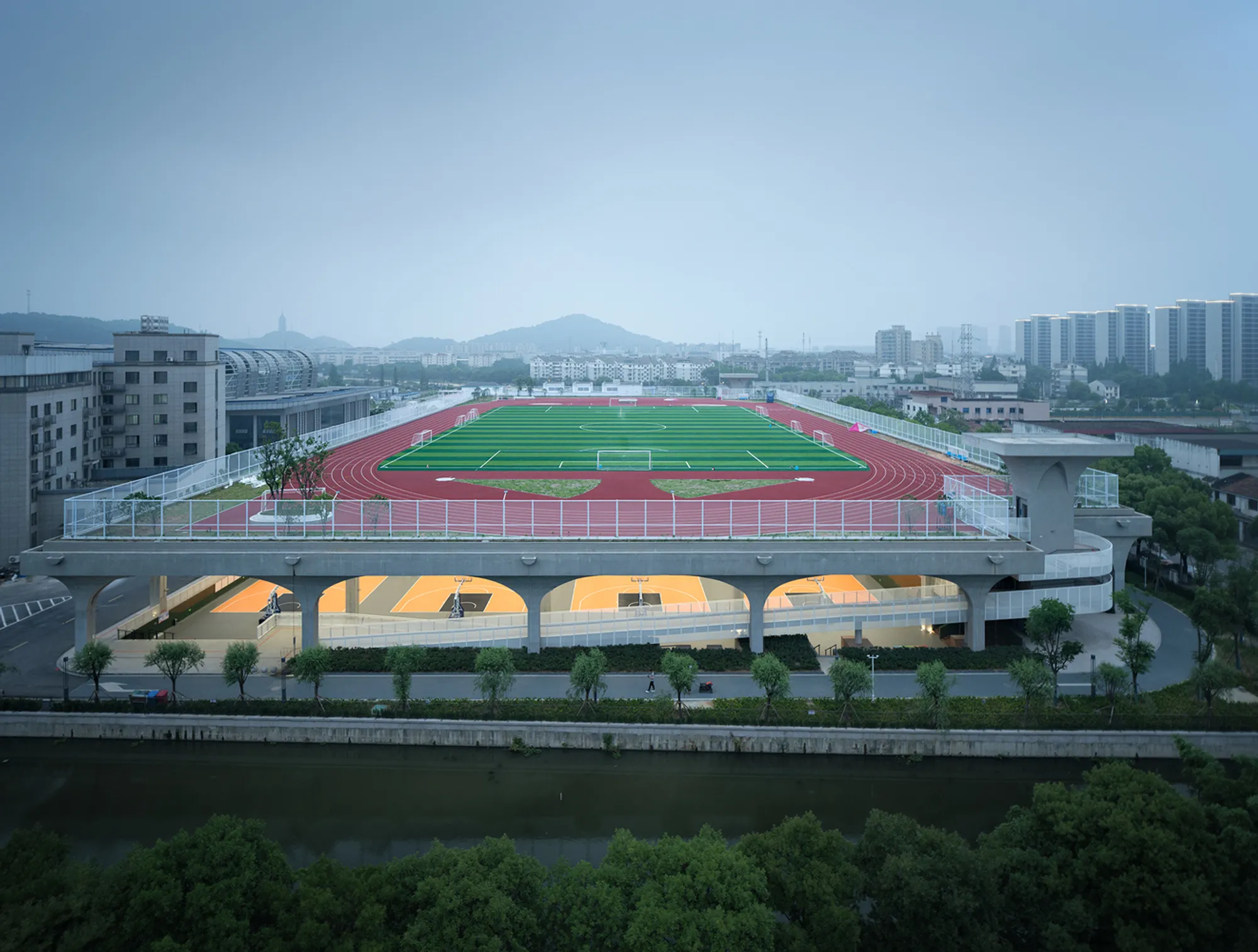 UAD Lifts a Football Pitch into the Sky to Shelter an Entire Sports Complex Beneath It