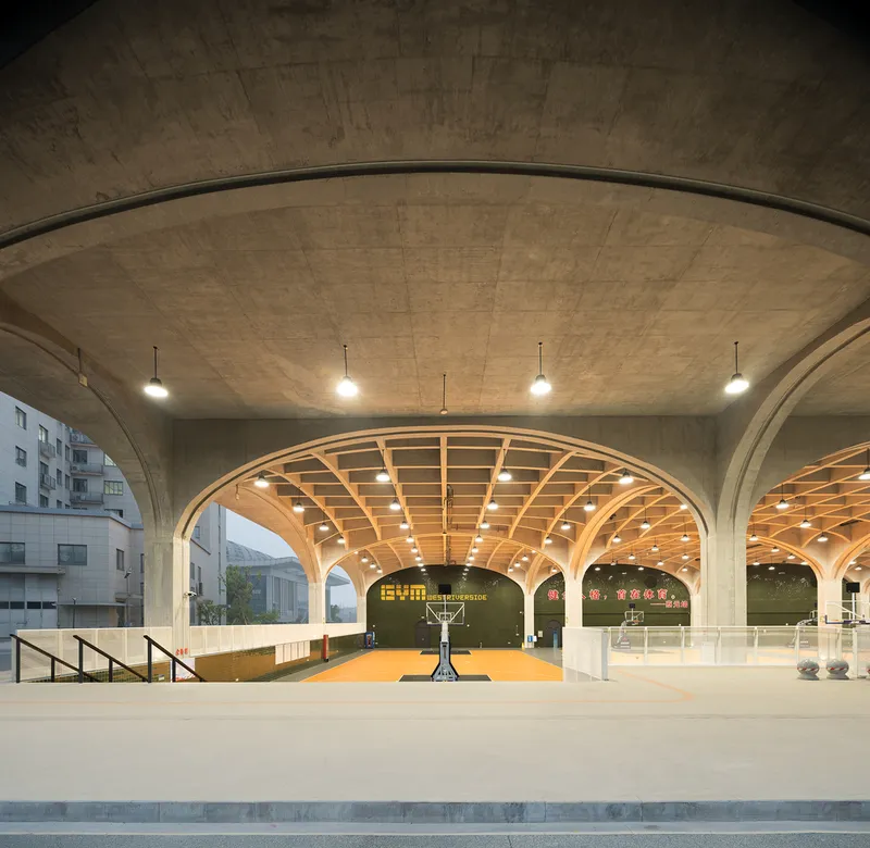 Interior view of vaulted timber ceiling structure over basketball court with pendant lights