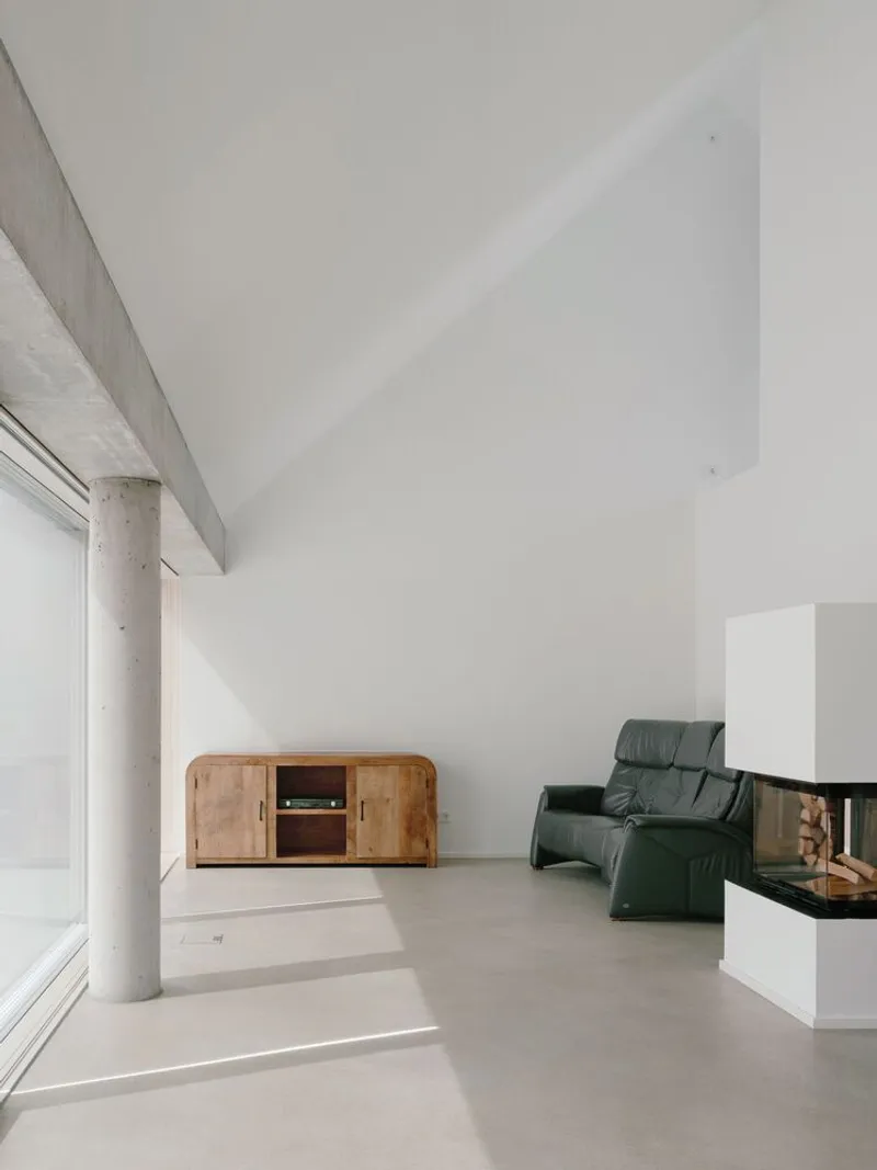 Living room with cylindrical concrete column and continuous window band filtering soft daylight