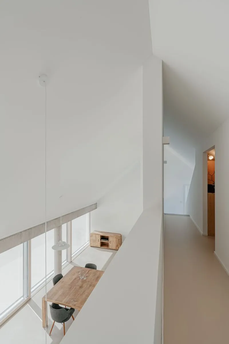 View from upper hallway down to dining area with timber table and pendant light below