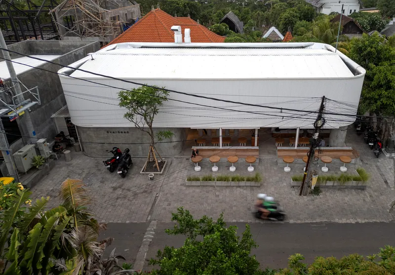 Elevated view of the curved roof and outdoor seating patio with passing motorbike on the street