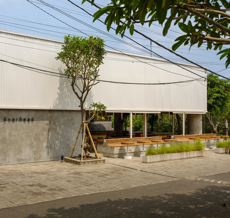 Street facade with corrugated metal cladding and concrete base wall framed by overhead power lines