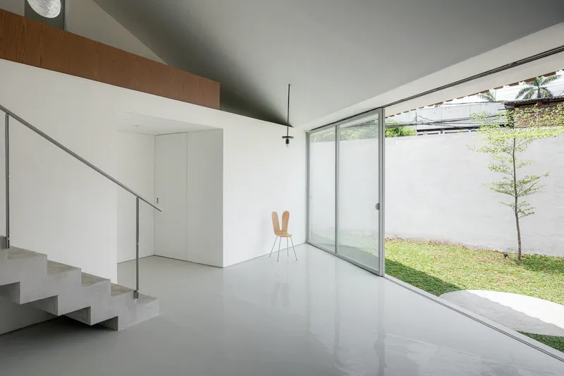 Interior living space with polished floor, open staircase and full-height glazing to the garden