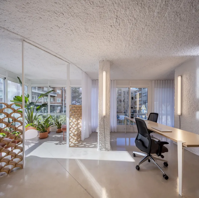 Workspace with embedded desk and potted plants on the balcony visible through sheer curtains