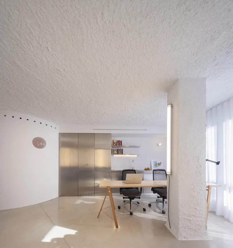 Workspace nook with brushed metal cabinetry and floating shelf under a vaulted sprayed ceiling