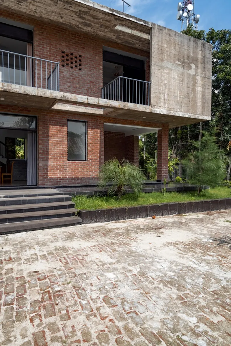 Entry approach with brick paving and stepped plinth below the cantilevered concrete volume