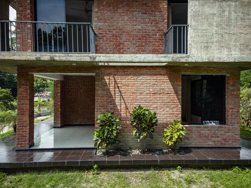 Ground floor terrace with brick columns and planted beds beneath the concrete slab above