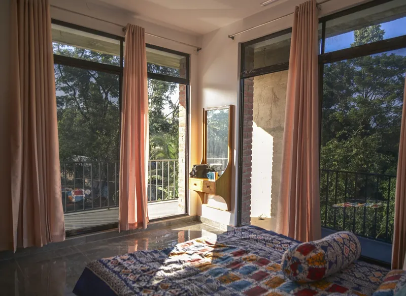 Bedroom corner with glass doors opening to a balcony in morning sunlight