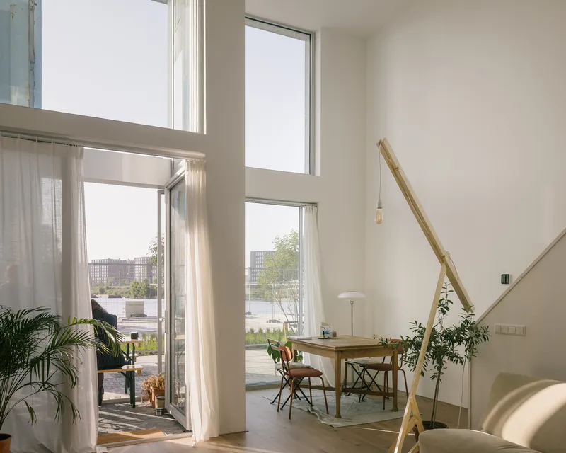 Double-height dining space with tall windows and glazed doors opening to a terrace with potted plants