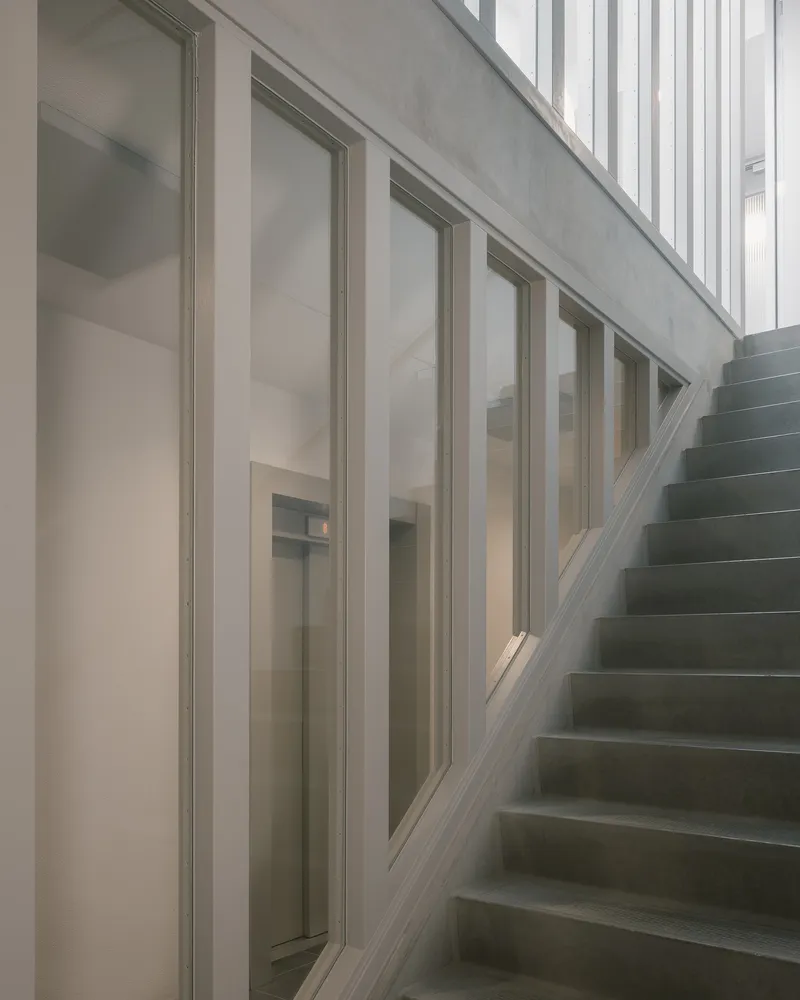 Concrete stairwell with continuous glazing along the exterior wall under soft natural light