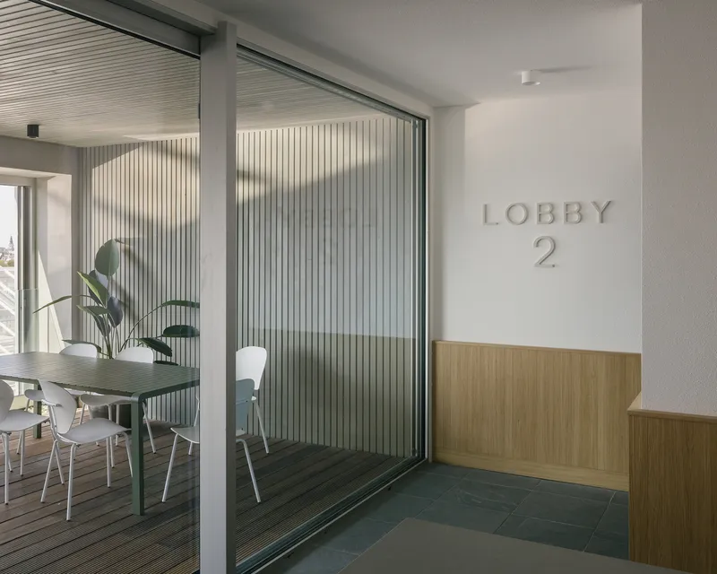 Lobby entrance with translucent corrugated partition separating the reception area from a communal room