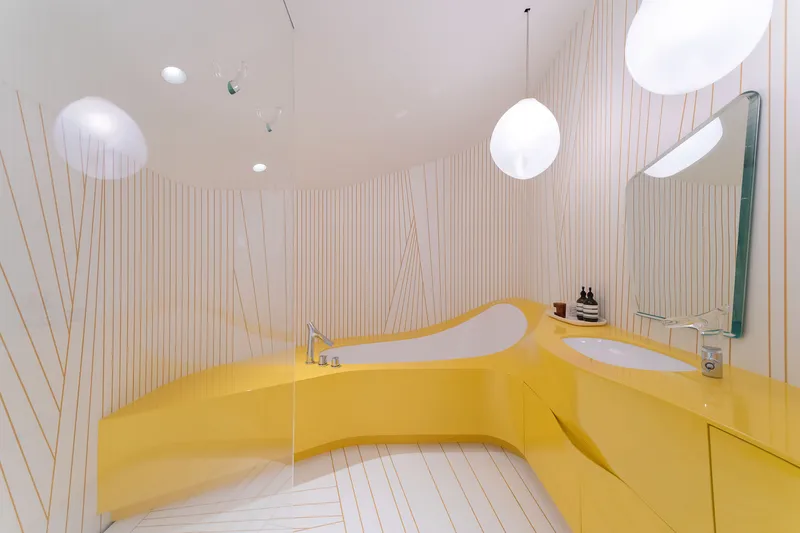Bathroom with bright yellow sculptural vanity and bathtub against vertical ribbed wall panels