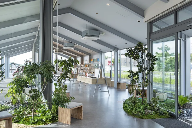 Interior corridor with exposed ceiling beams and potted trees flanking a polished concrete floor