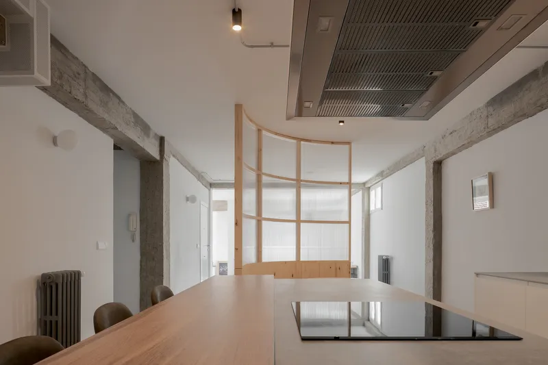Conference table with inset black panel beneath curved timber screen and exposed concrete beams