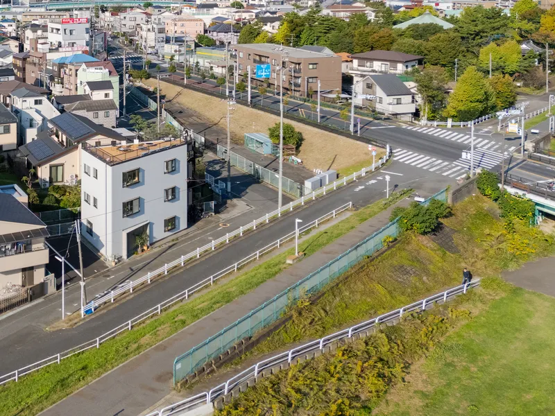Aerial view of the white cubic building set between a roadway and a green levee
