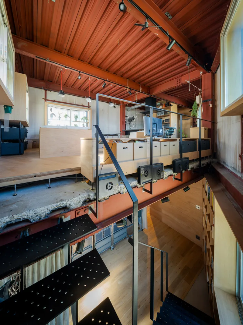 Vertical view showing split-level platforms connected by perforated metal stairs under timber beam ceiling