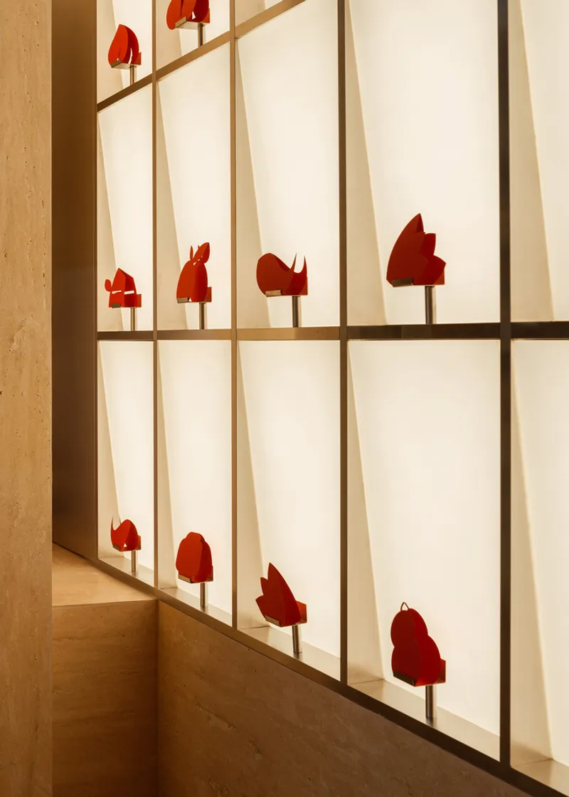 Backlit translucent wall panels with timber frame and red silhouette objects mounted at intervals