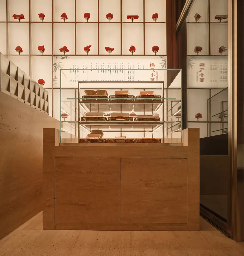 Timber counter with glass display case and backlit wall grid holding red objects in retail space