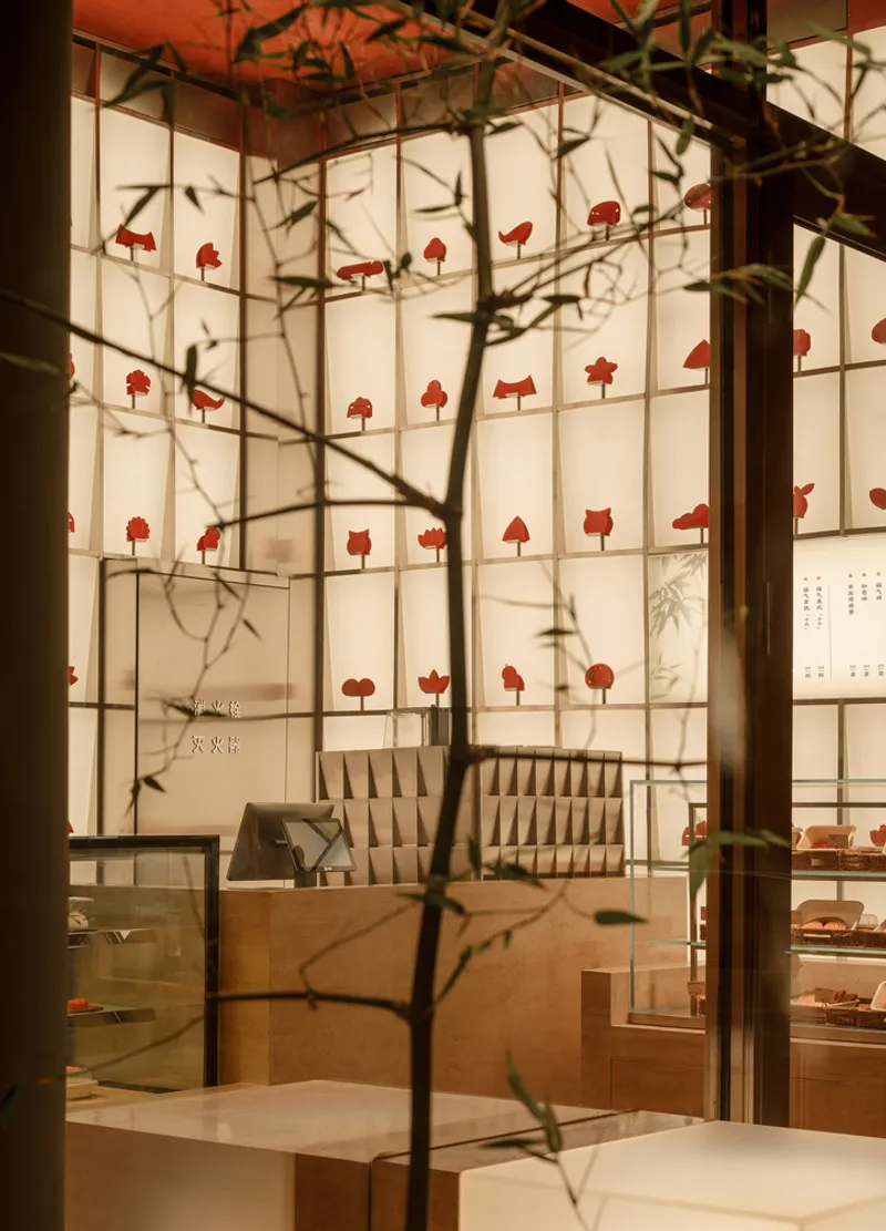 Interior view through glass showing the gridded display wall with tree branch shadows cast across it