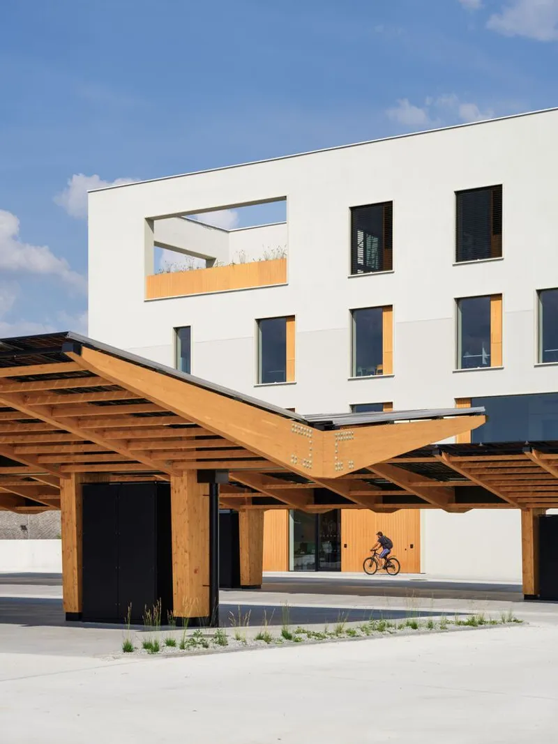 Timber pergola structure sheltering the entry with a cyclist passing through the courtyard