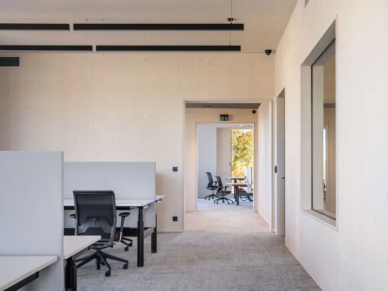 Interior office space with exposed concrete ceiling and view through doorway to meeting room