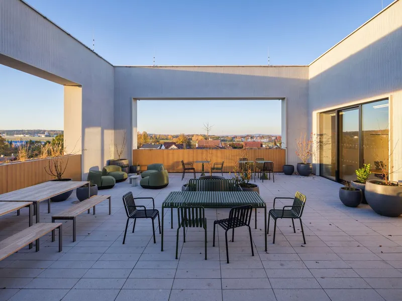 Rooftop terrace with outdoor furniture and framed view of distant landscape at sunset