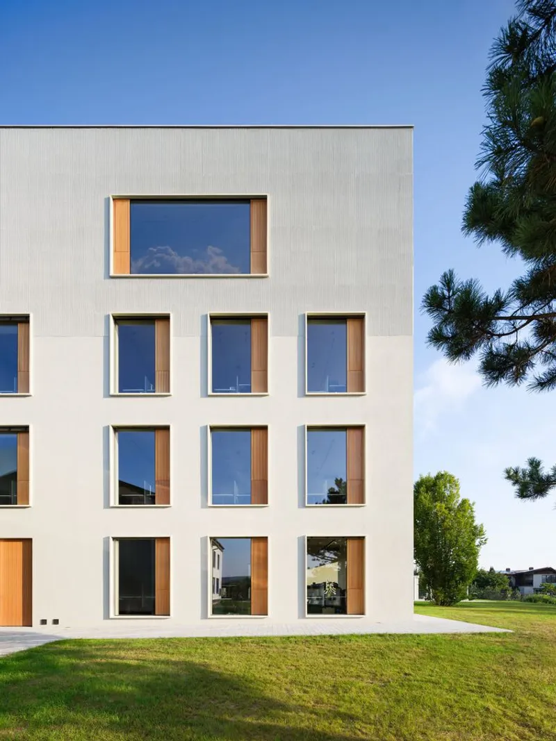 White render facade with timber-framed windows across three floors under a clear blue sky