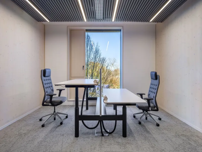 Meeting room with two desks and office chairs facing a window opening to bare winter trees