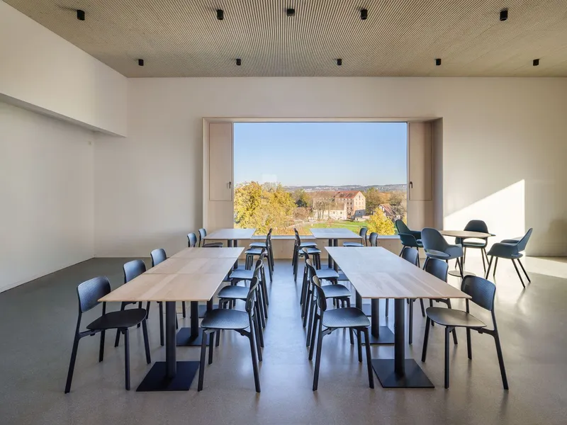 Conference tables arranged in a row beneath a timber slat ceiling with sunlight entering from the window