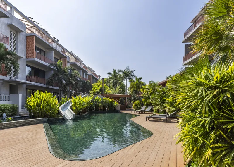 Courtyard pool surrounded by timber decking and dense tropical plantings between residential wings
