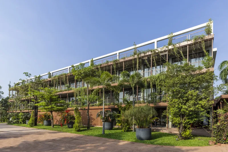 Planted ground level with large planters and trees beneath heavily vegetated balconies and white frame