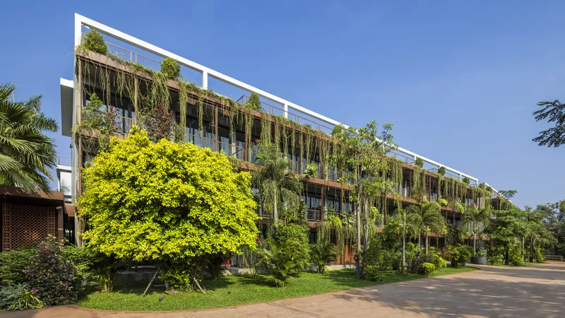 Street view of the planted facade with cascading vegetation and a flowering tree in the foreground