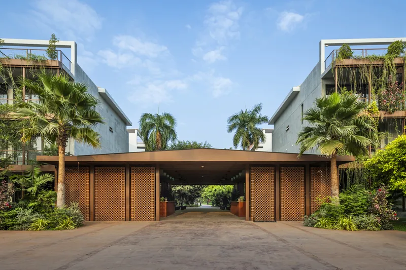 Entry pavilion with perforated brick panels and flat canopy flanked by palms under blue sky