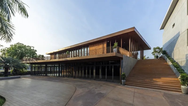 Two-story pavilion with timber louvres and wide exterior staircase at sunset