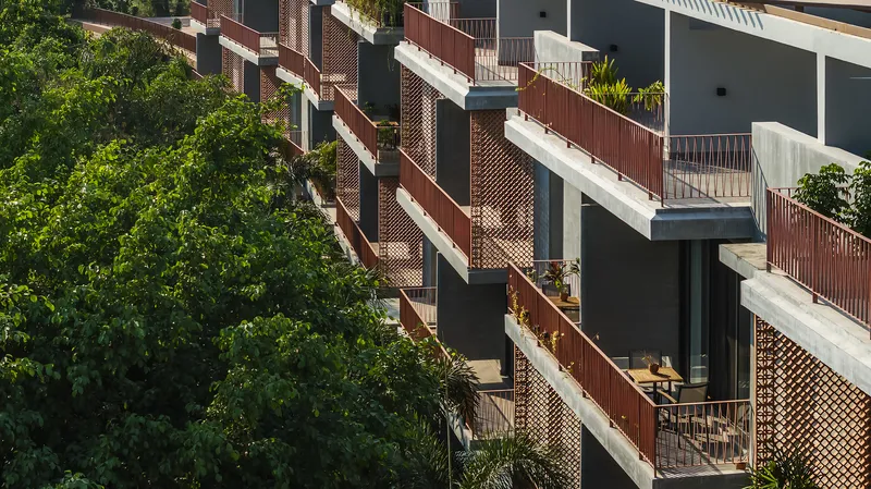 Staggered balconies with perforated brick screens and planted privacy partitions against surrounding trees