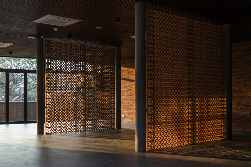 Interior lobby with perforated metal screens backlit by warm light and timber ceiling panels