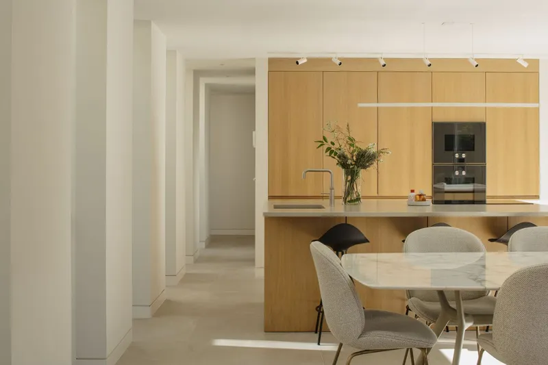 Open-plan kitchen and dining area with oak cabinetry and white ceiling beneath track lighting