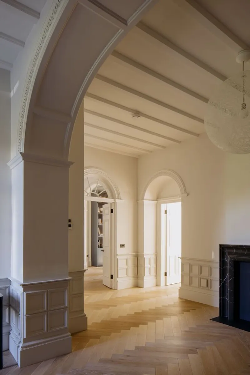 Sequence of three arched openings with exposed ceiling beams and herringbone oak floors in soft light