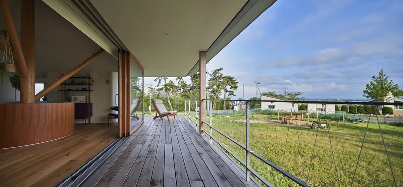 Covered timber deck extending into a grassed yard under partly cloudy skies