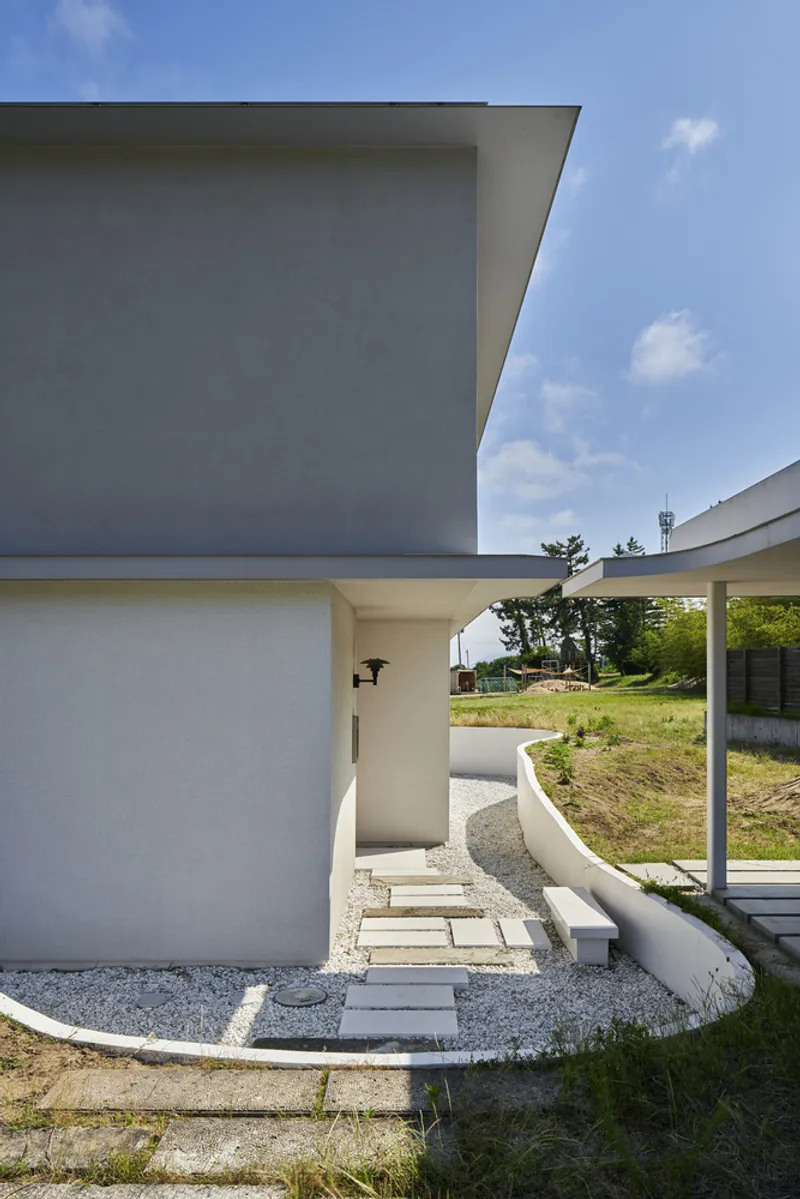 Entry pathway with stepping stones through gravel leading to recessed doorway beneath carport