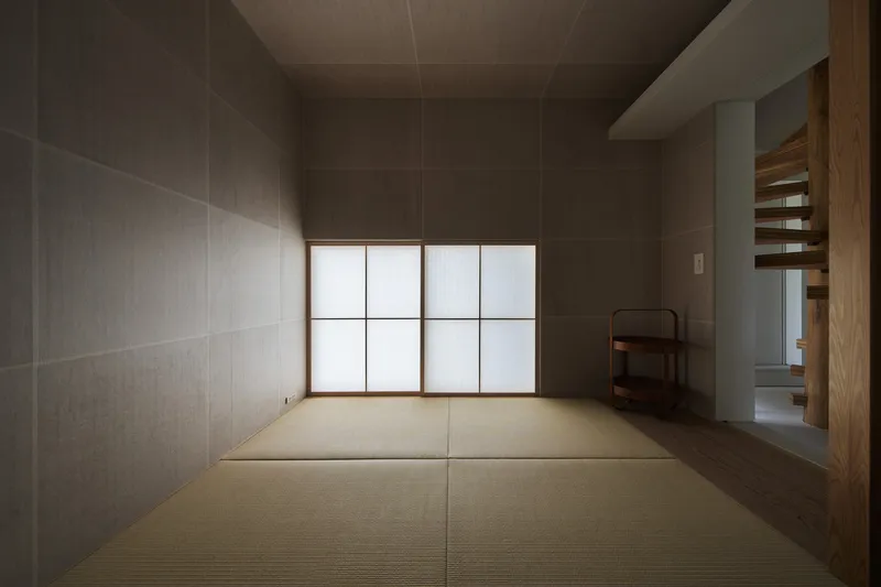Tatami room with grey textile-clad walls and translucent shoji screens diffusing soft daylight