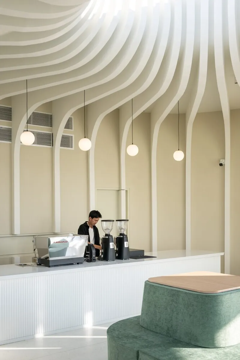 Interior counter with ribbed white ceiling blades cascading down pale yellow walls and globe pendant lights