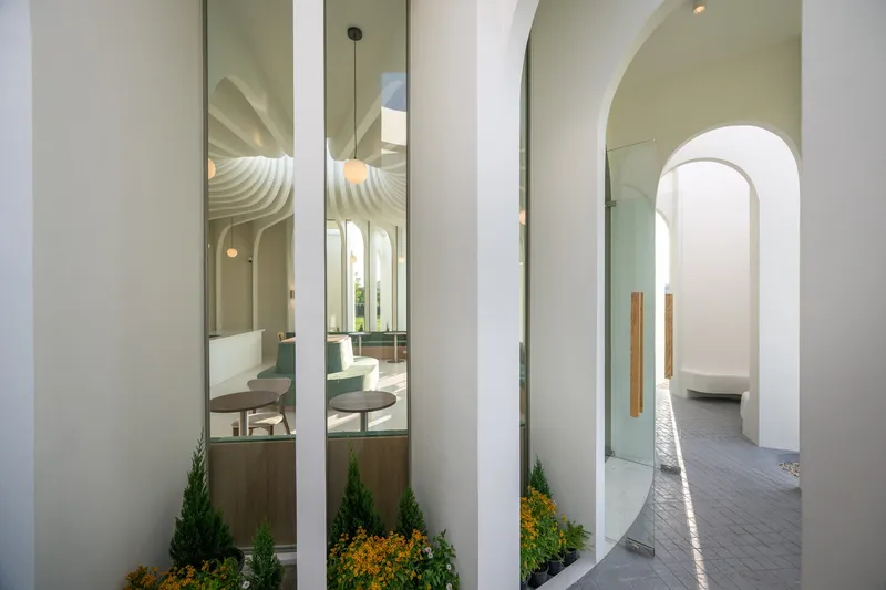 Exterior colonnade with planted beds of conifers and yellow flowers between white cylindrical columns