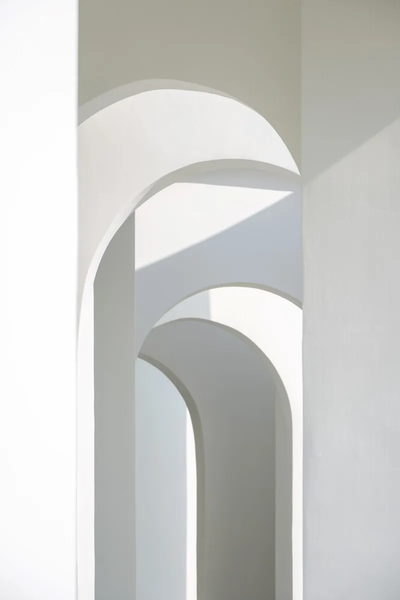 Interior view of layered arched openings in white plaster with natural light filtering through