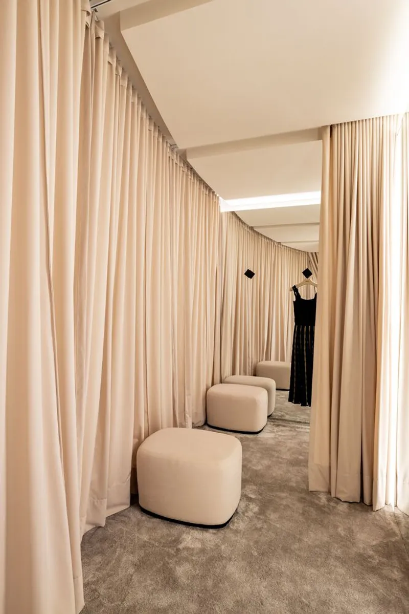 Fitting room corridor with floor-to-ceiling curtains and curved ceiling cove lighting above