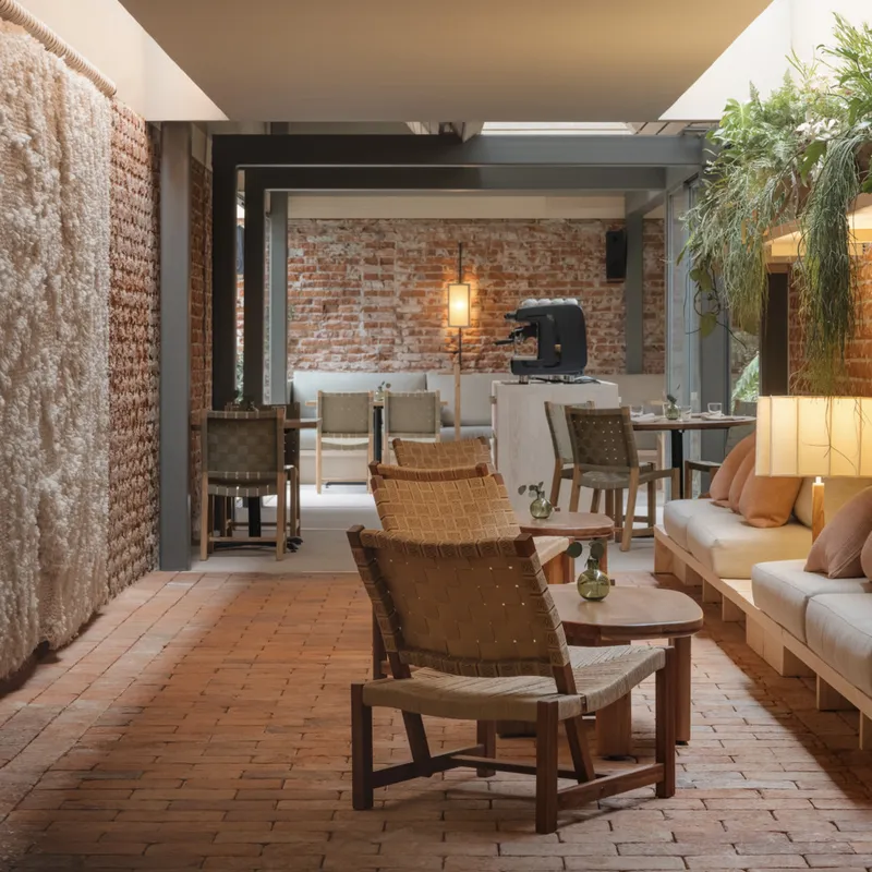 View from brick paved terrace through steel frame into the dining area with exposed brick walls