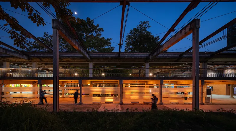 Open-air platform with steel frame structure and timber slat walls glowing at blue hour