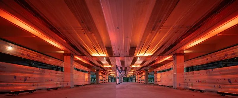 Symmetrical view down the platform showing timber slat walls illuminated by red and amber strip lighting
