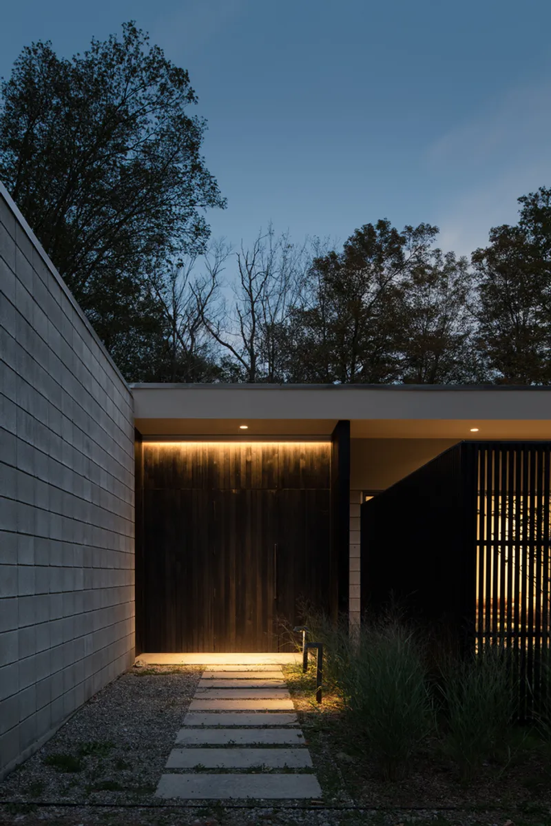 Entry path illuminated at dusk with timber wall and recessed ceiling light at threshold